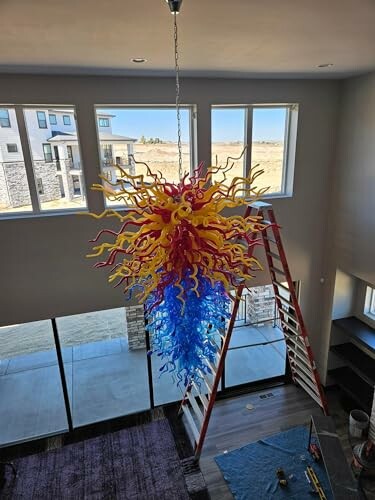 Vibrant glass chandelier with yellow, red, and blue tendrils hanging in a modern room.