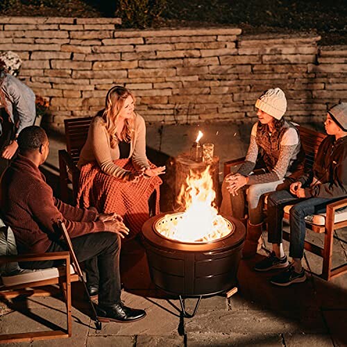 Group of people sitting around a fire pit at night.