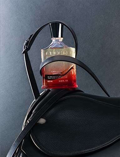 Perfume bottle resting on a leather bag