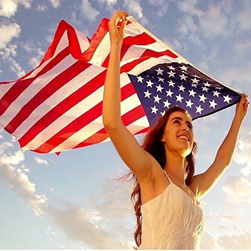 Woman holding a U.S. flag against a cloudy sky.